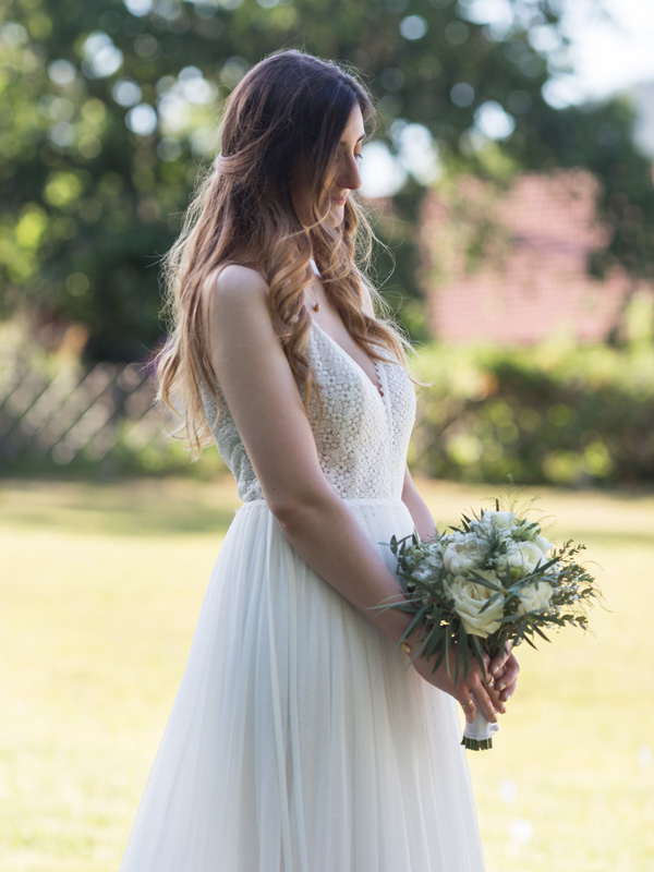 Mariée regardant avec passion le bouquet de fleurs choisi pour l'accompagner lors de la cérémonie de mariage en présence du photographe professionnel